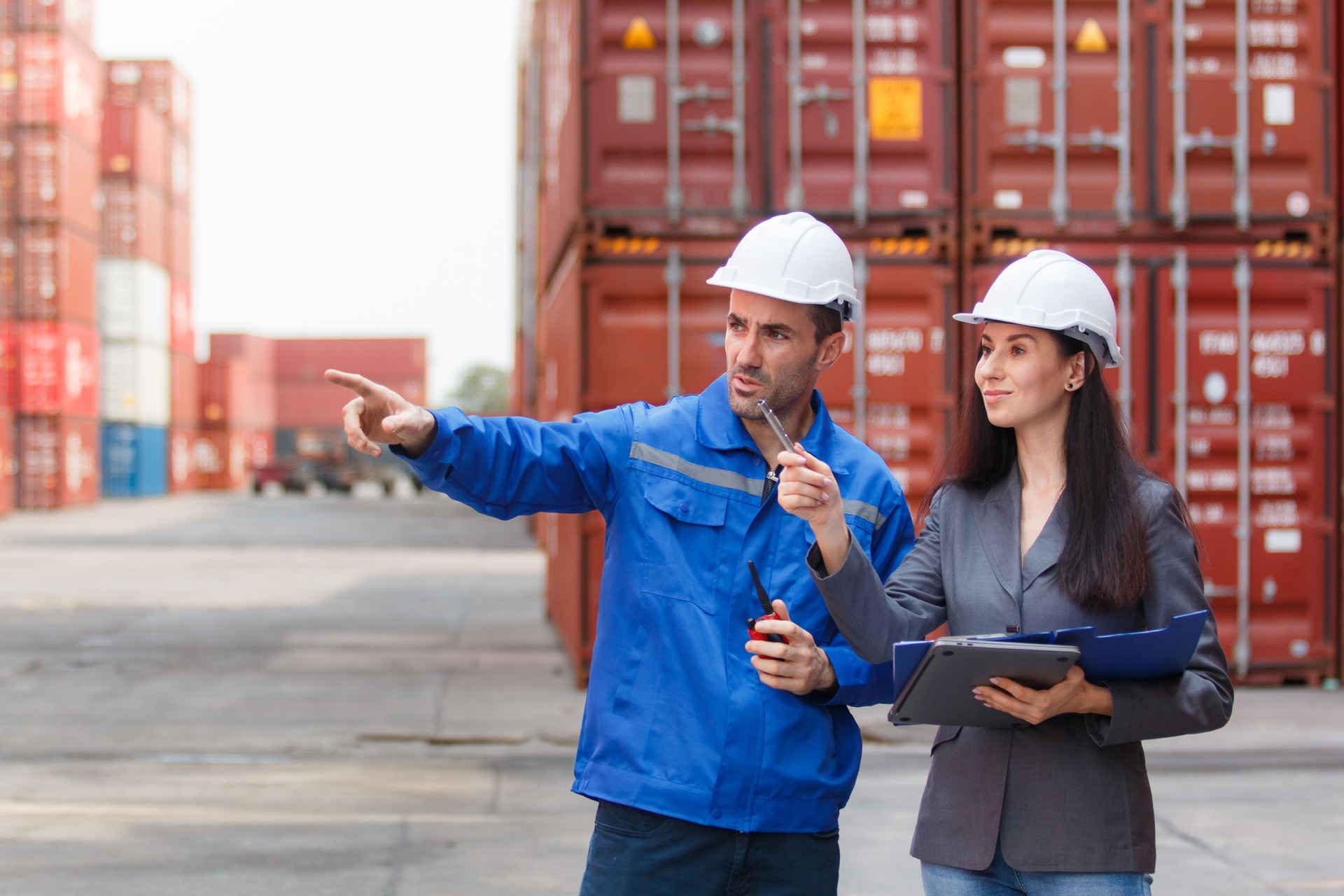 Businesswoman talking with container yard officer about import export logistics, global trade, and international shipping management.